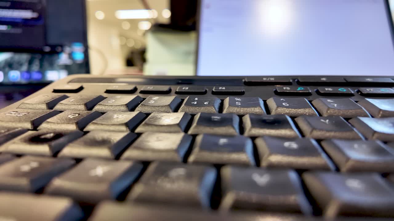 Close Up of Black Computer Keyboard with Laptop Screen in Background for Technology and Office Concepts Focus on Keys and Ergonomics