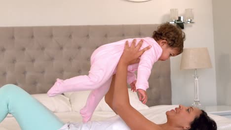 madre jugando con la hija bebé en la cama