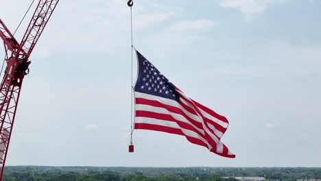 hung from a construction crane, the flag of the united states waves in the wind