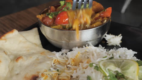 A-forkful-of-authentic-Indian-Jal-Frezi-served-with-rice-and-naan,-slow-motion-slider-pull-HD