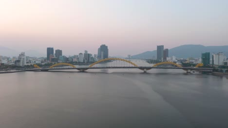 colorful wide aerial of iconic dragon bridge cau rong, traffic and city skyline during sunset in danang, vietnam