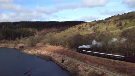 Toma-Aérea-De-Un-Tren-De-Vapor-Rural-Junto-A-Un-Lago