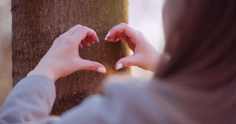 woman make heart shape with hands in forest 2