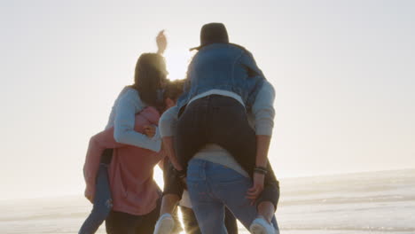 Grupo-De-Amigos-Teniendo-Juntos-Una-Carrera-A-Cuestas-En-La-Playa-De-Invierno