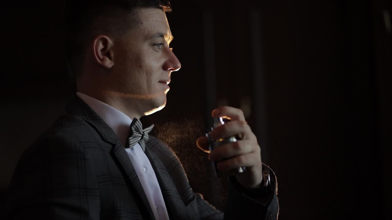 신랑은 자신에게 향기 또는 디오도란트를 분할합니다. 결혼식 날. 느린 동작. 잘 옷을 입은 사업가