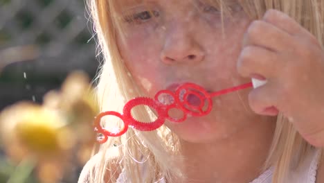 young girl blows bubbles with wand