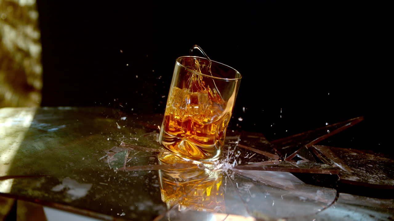 un vaso de whisky rompe la superficie del vaso en cámara súper lenta, símbolo del alcoholismo y los efectos negativos de beber.