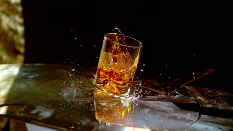 a glass of whiskey breaks a glass surface in super slow motion, symbolic of alcoholism and the negative effects of drinking