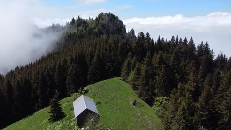 tomada de un avión no tripulado de un pasaje de montaña con una pequeña casa, un bosque y un lecho de nubes