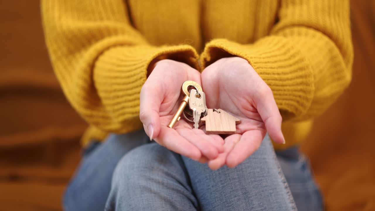 la mujer muestra las llaves de la casa en el llavero de su palma.