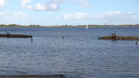 wide view of beautiful lake with a white sailboat in the distance on a sunny day