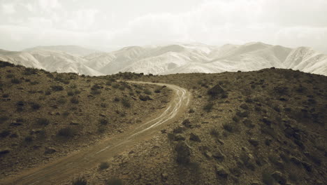 a winding dirt road through a desert mountain range