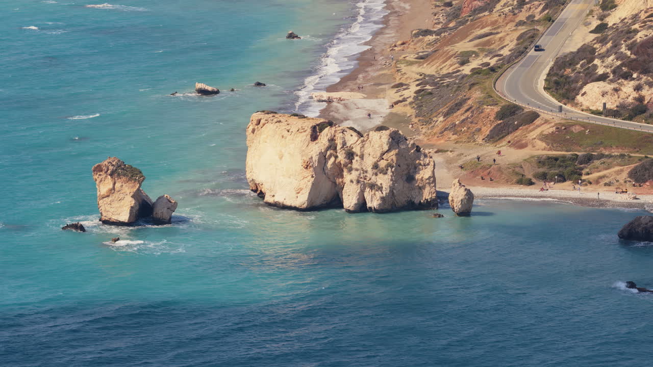 Aerial drone view of Aphrodite's Rock with turquoise sea and nearby coastal road, one of Cyprus' most famous natural landmarks
