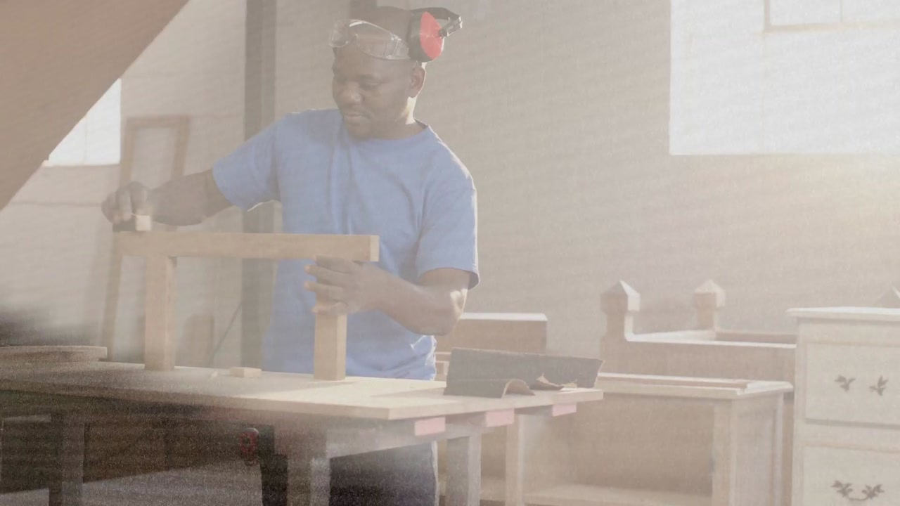 Vertical video: Sun revealing man blue shirt muffs aligning sanding top with block for fit at bench