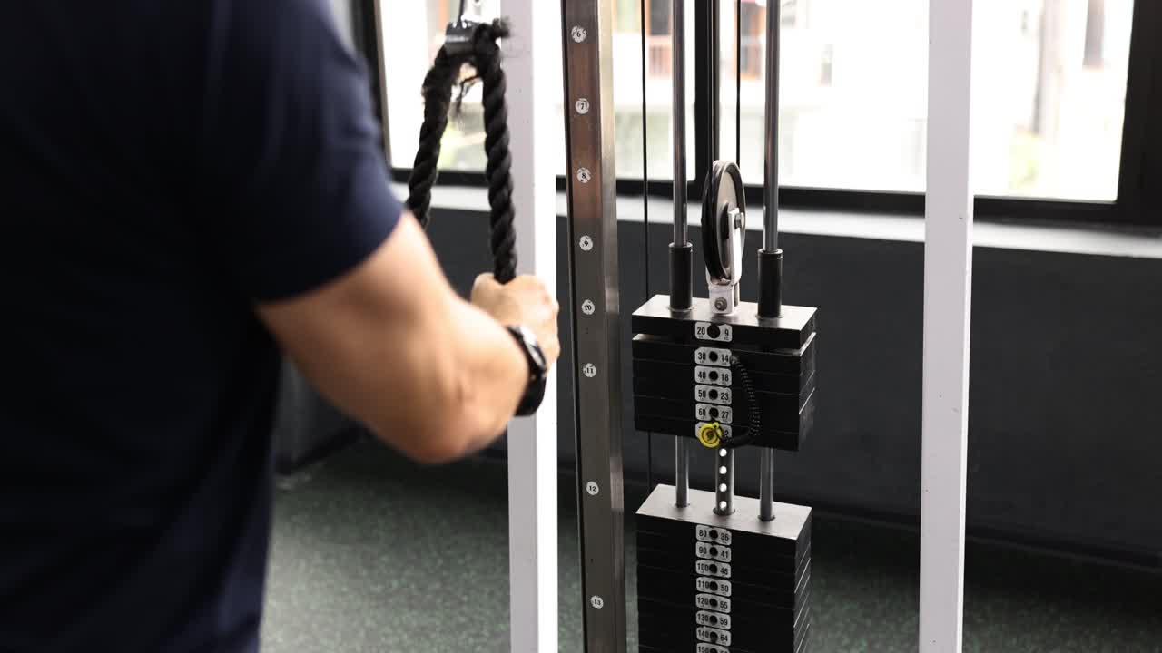Man works out on crossover exercise machine in gym