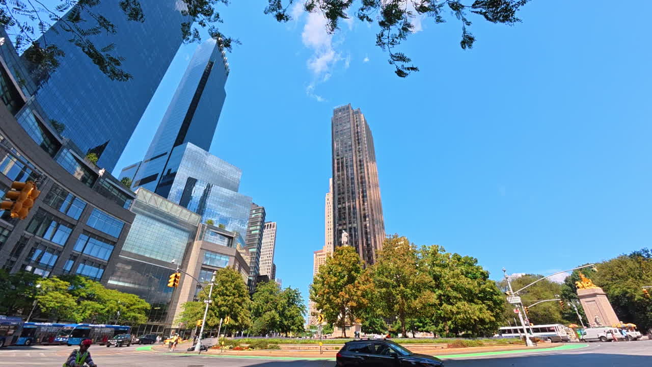New York, USA, 1 August 2025: Columbus Circle surrounded by tall buildings in Manhattan. The sunny square of Columbus Circle is framed by skyscrapers and green trees