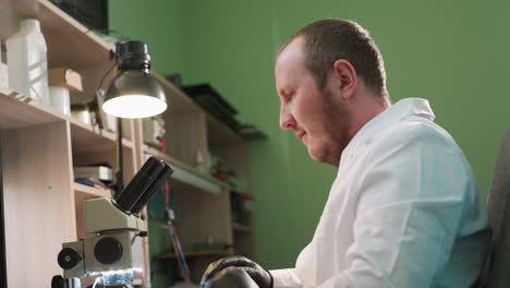 an upward view of a lab technician in a white coat stretching and taking a break from work in a laboratory, and looking into microscope