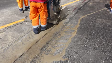 worker is using power tool to cut asphalt to correct measure