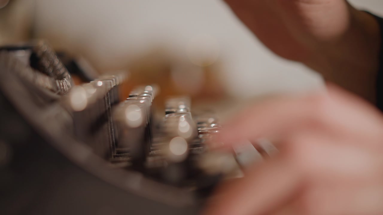 Autor cria história com máquina de escrever. Cena íntima de dedos pressionando teclas durante a escrita noturna. Close-up capturando as mãos enquanto o romancista cria o manuscrito sob o brilho suave da lâmpada.