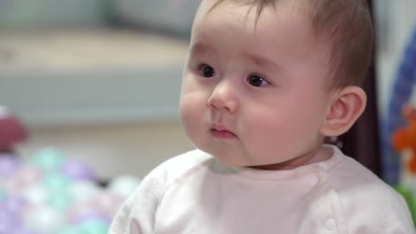 cute mixed race baby looking around room not changing facial expression