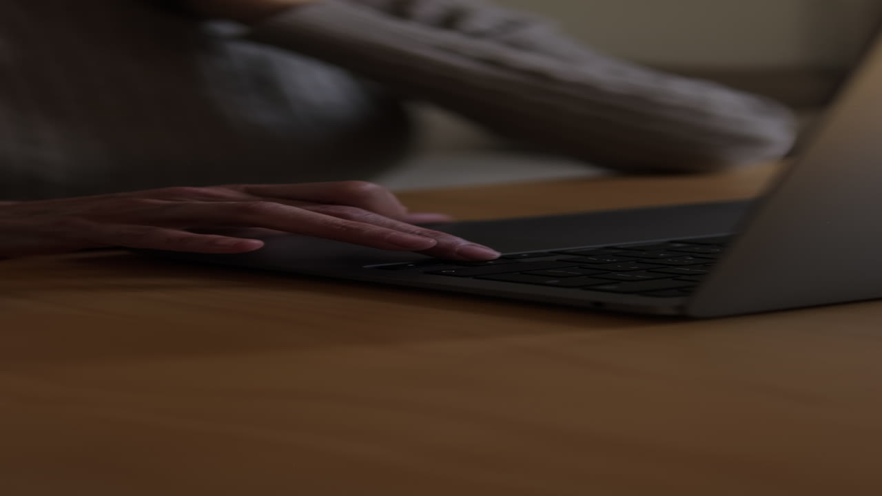 Close-up of Person's Hands Typing on Laptop Keyboard at Night