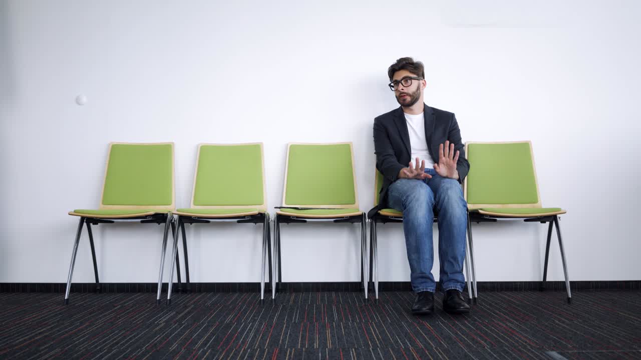 Stressed young man sitting in hallway waiting for job interview
