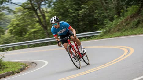 dynamic cyclist navigating a scenic road, showcasing speed and determination while taking on steep turns in a beautiful green landscape