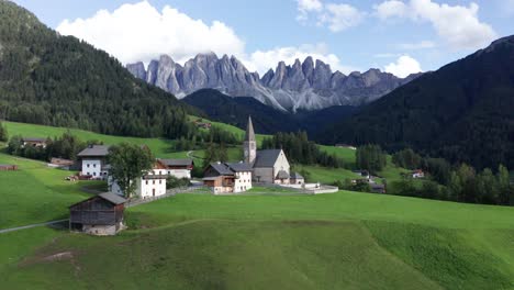 idilliaco villaggio di montagna con chiesa nelle montagne dolomitiche, orbita aerea