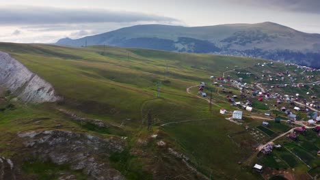 Vuelo-Ascendente-De-Drones-Sobre-El-Pueblo-De-Las-Tierras-Altas-Al-Atardecer,-Paisaje-Rural-Del-Valle-Verde-De-Verano-Y-Horizonte-De-Montaña