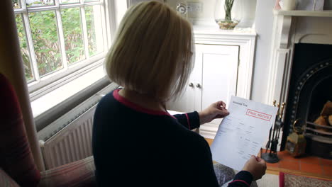 una anciana irreconocible preocupada por las deudas abriendo una carta de deuda