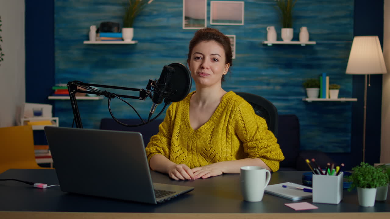Portrait of young vlogger working in cozy studio, smiling at camera