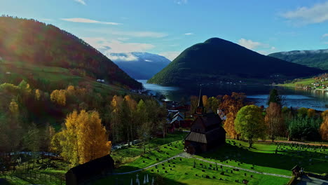 Vista-Aérea-Del-Hermoso-Y-Colorido-Paisaje-De-Noruega-Con-Vistas-A-Una-Pequeña-Comunidad,-Un-Lago-Cristalino-Y-Las-Montañas-Al-Fondo-Durante-Un-Agradable-Viaje-De-Vacaciones