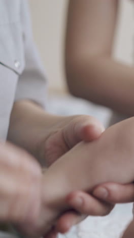 professional pediatrician practices hypertonus massage holding little infant leg and rubbing close view