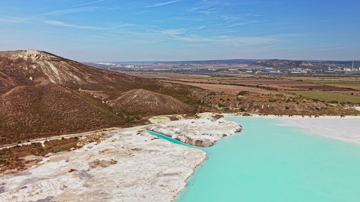 Stagno di rifiuti chimici accanto a una costa coperta di minerali in un paesaggio aperto visto dall'alto durante il giorno