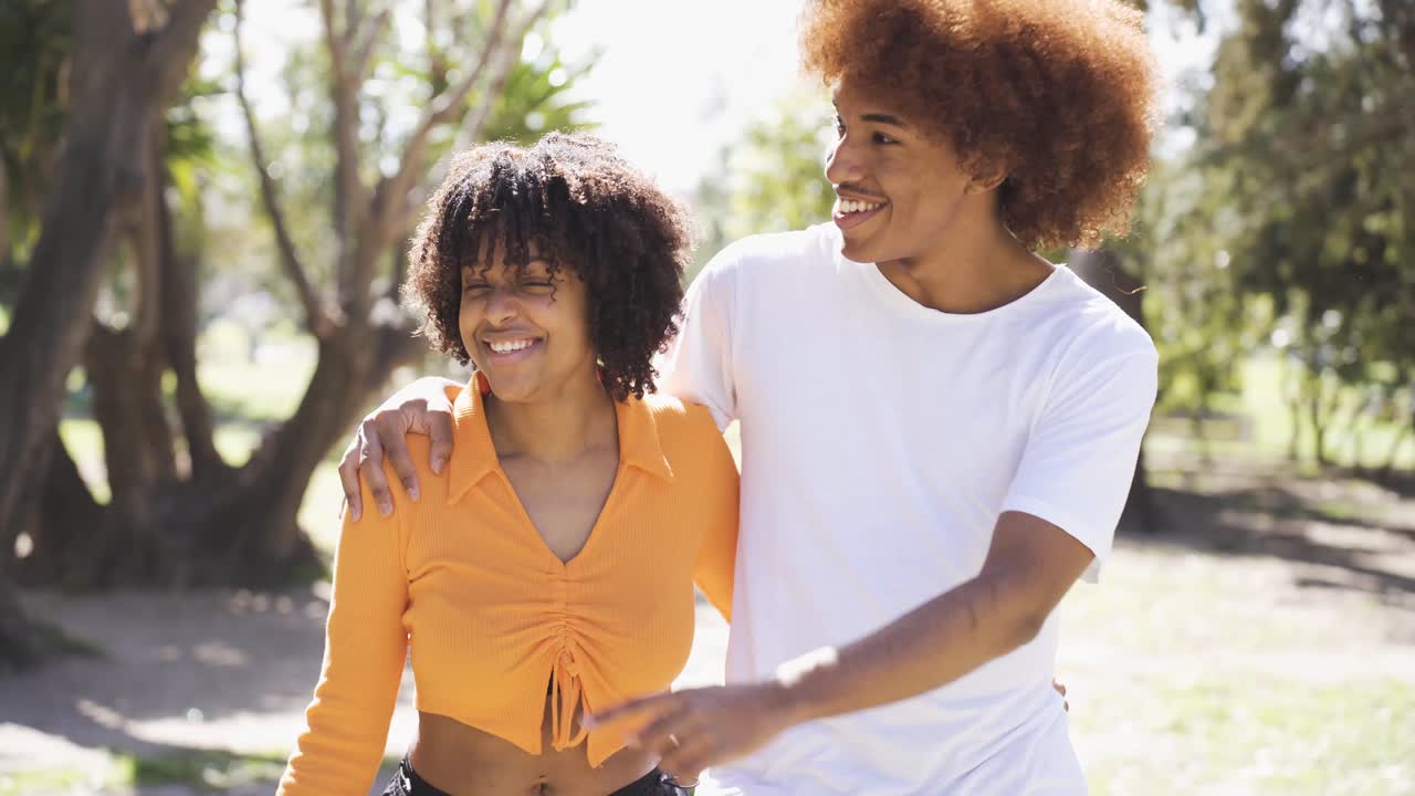 una coppia nera felice che si abbraccia e cammina per strada
