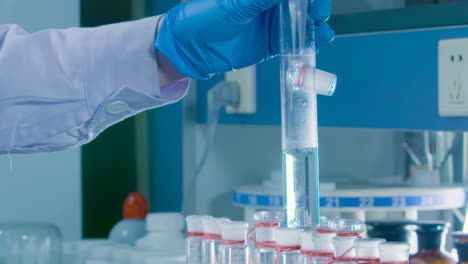 scientist in lab coat and blue glove holding a test tube