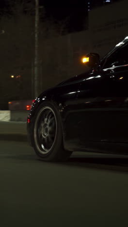 black car driving at night on city street