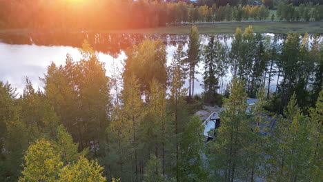 Aerial-pullback-from-Nordic-Cottage-hidden-in-the-forest-by-the-Lake-during-sunset