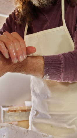 male potter washing hands after working on pottery wheel