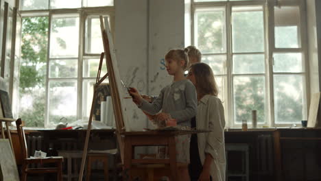 talented female teacher spending time together with boy and girl in art school.