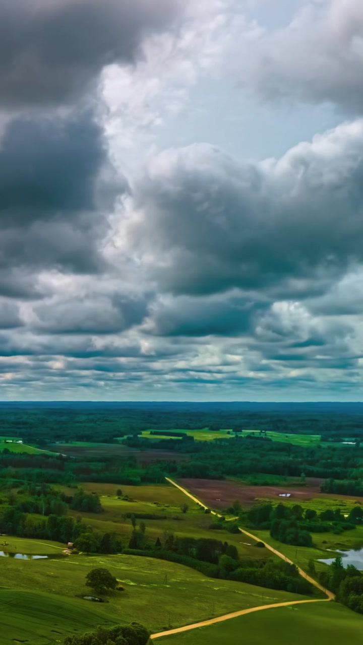 Aerial hyperlapse over rural farmland with dramatic moving clouds and green fields