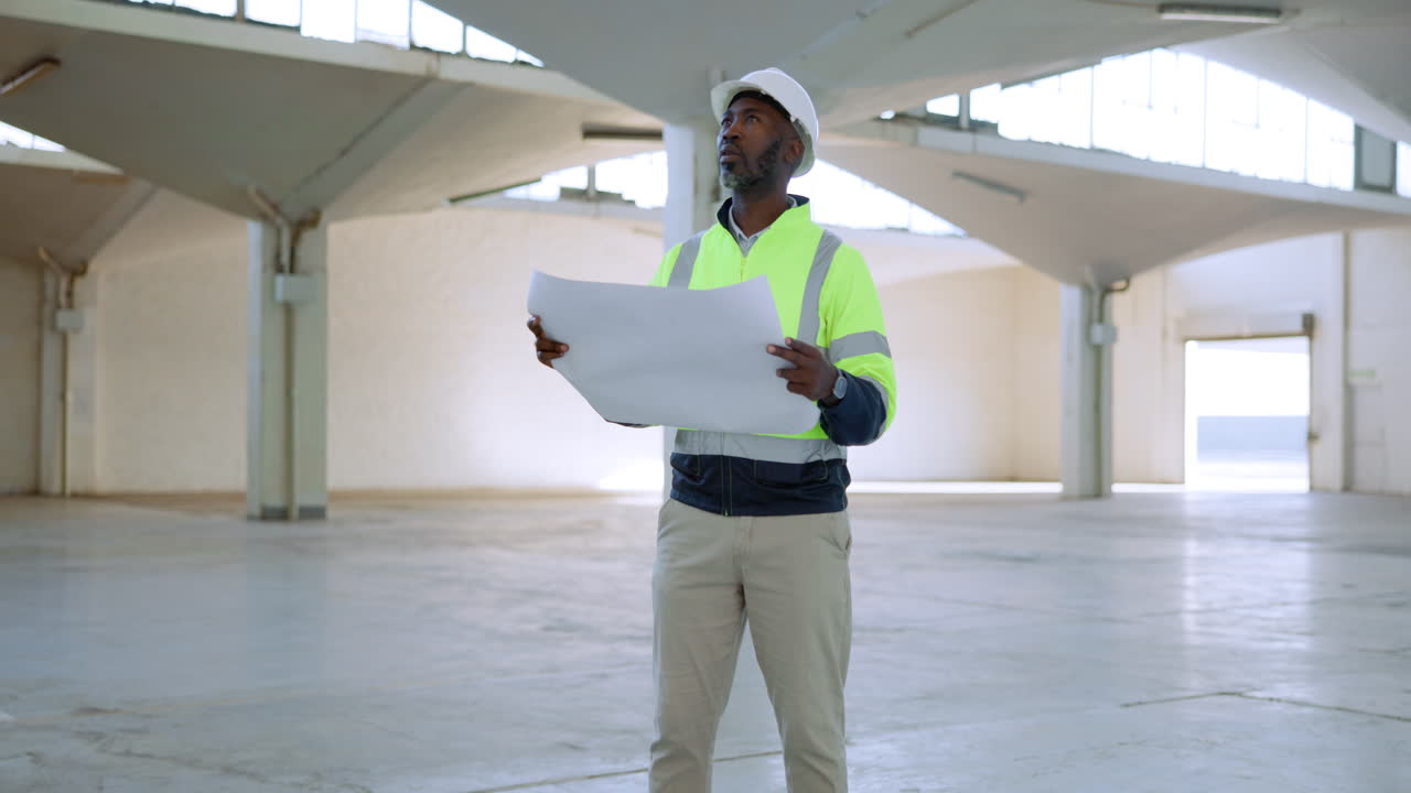 Construction worker with blueprint in industrial building