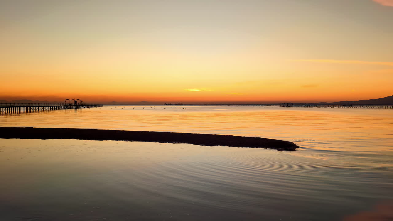 A pier in the calm water during a golden sunrise
