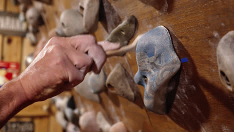 a man brushing the chalk of a climbing hold at the gym