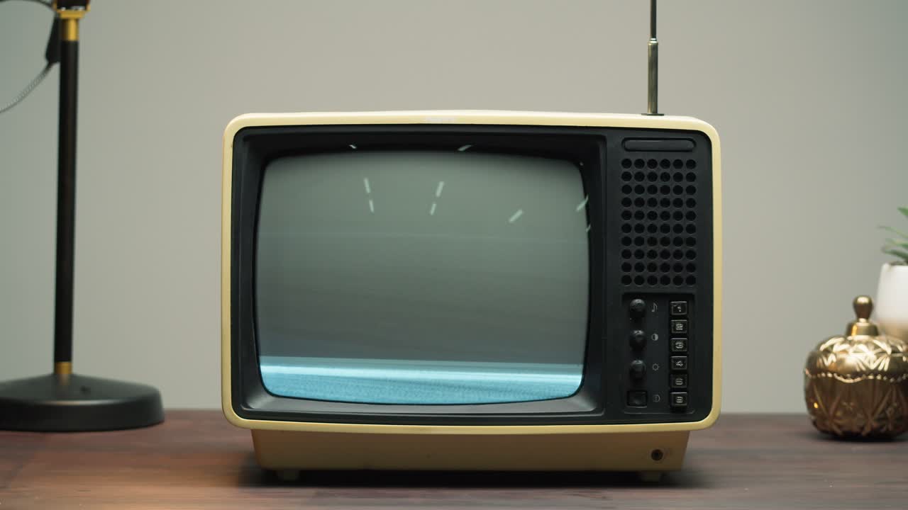 Mano che sintonizza un televisore vintage con schermo disturbato.