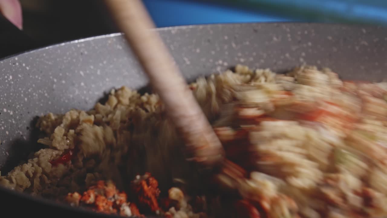 나무 숟가락으로 냄비에 향신료, 질감 있는 식물성 단백질 및 기타 재료를 섞고, 보기를 닫습니다.