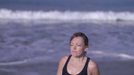 Middle-aged-white-woman-walking-out-of-Pacific-Ocean-in-Venice-Beach,-California-in-slow-motion-close-up