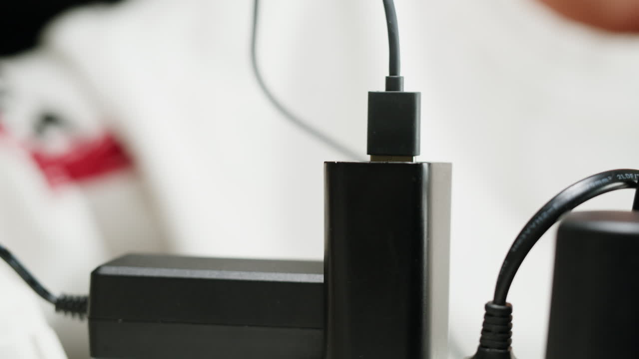 White power strip with many various of cords and cables in close-up. An extension cord with many power sockets. Adapter with phone, headphones, usb connectors.Tangled wires on table. Trying to untangle many messy cables.