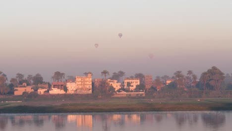 Sunrise view of the Nile river with buildings and hot air balloons flying in Luxor, Egpyt.