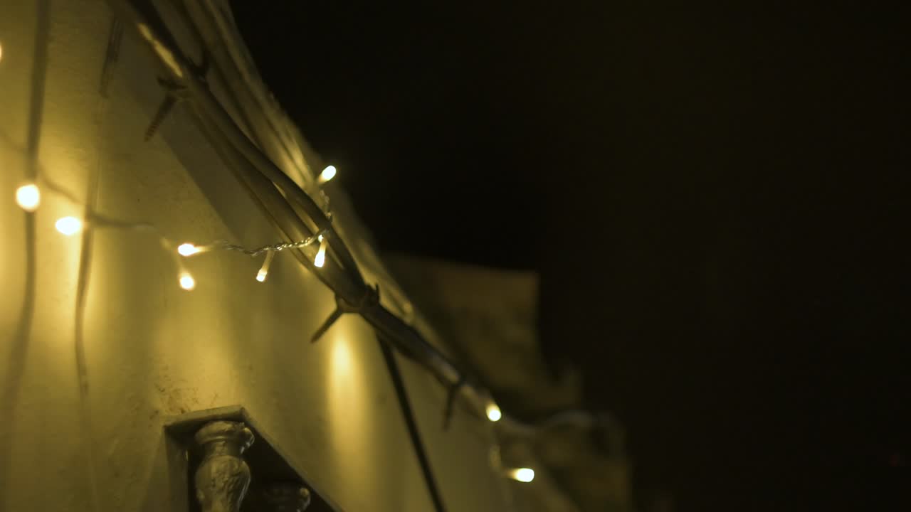 Miniature nativity scene with blinking Christmas lights illuminating the details of the house at night